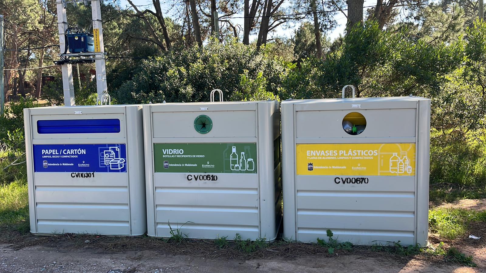 Integrantes de la comisión de vecinas y vecinos junto a los contenedores de reciclaje del balneario