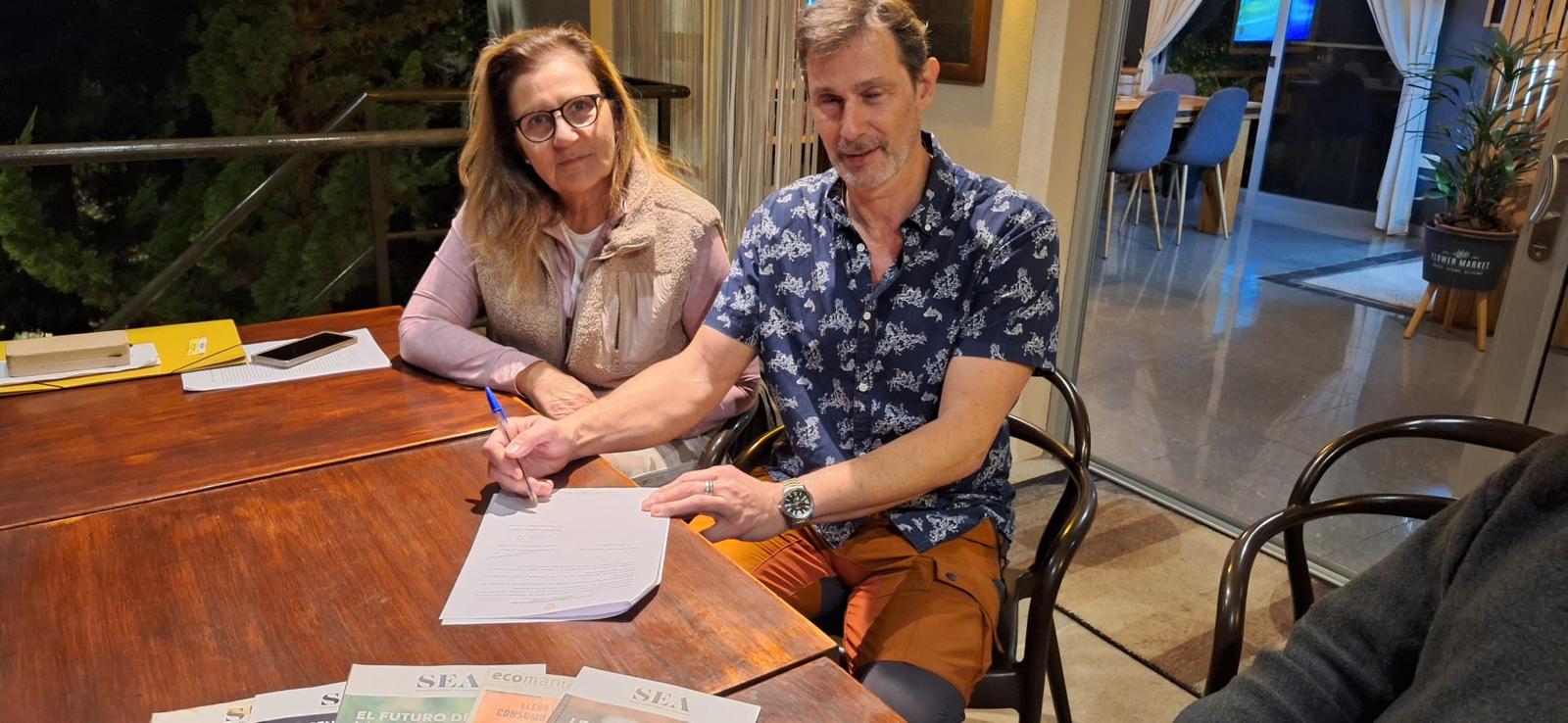 Firma del convenio UNIFA y comisión de vecinos junto a materiales de educación ambiental